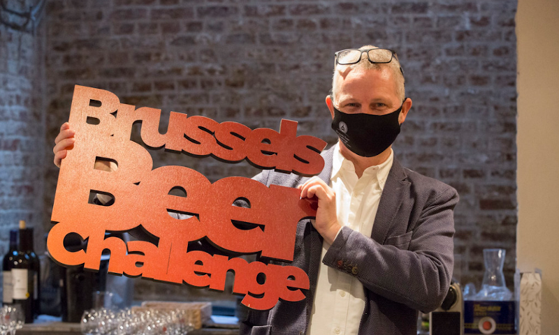 Jurylid met mondkapje op en een Brussels Beer Challenge bord in de hand